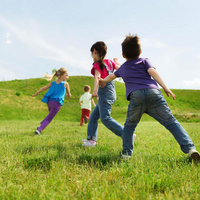 Three children playing in a field.