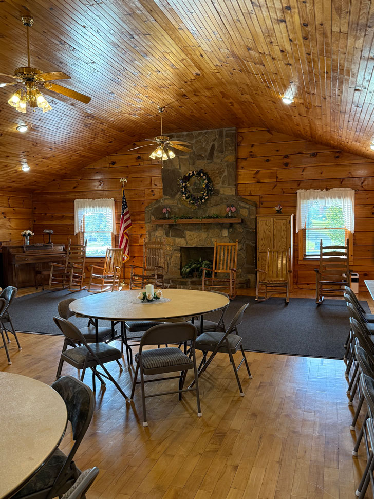 Cozy gathering area at Keith Memorial Park with rocking chairs and stone fireplace beneath a wood-paneled ceiling.